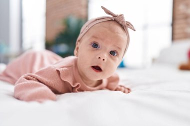 Adorable caucasian baby lying on bed with relaxed expression at bedroom