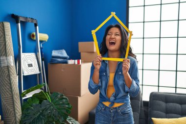 Genç Asyalı bir kadın yeni evine kızgın ve kızgın bağırarak sinirlenmiş ve öfkeyle bağırarak taşınıyor. öfke ve agresif konsept. 