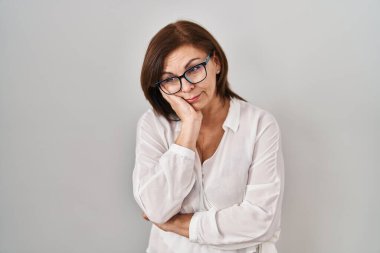 Orta yaşlı İspanyol bir kadın izole edilmiş arka planda duruyor. Kollarını kavuşturup depresyondan sıkılmış ve yorgun göründüğünü düşünüyor.. 