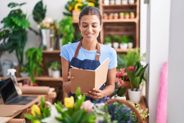 Çiçekçiye gülümseyen güzel İspanyol kadın çiçekçiye not defteri okuyor.