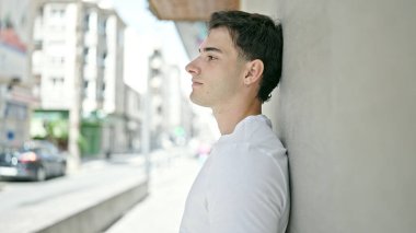 Latin kökenli genç adam ciddi bir ifadeyle sokağa bakıyor.