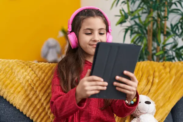 Αξιολάτρευτο Ισπανόφωνο Κορίτσι Χρησιμοποιώντας Touchpad Και Ακουστικά Κάθεται Στον Καναπέ — Φωτογραφία Αρχείου