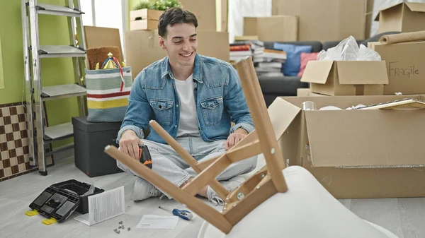 Young hispanic man smiling confident drilling chair at new home