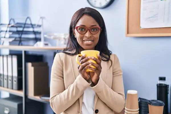 Young african american woman business worker drinking coffee at office