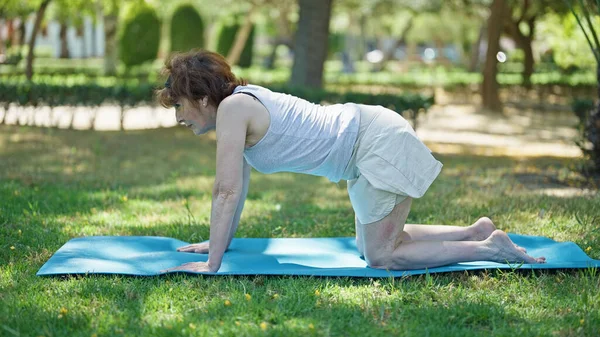 Middle age woman stretching back on yoga mat at park