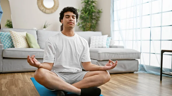 坐在地板上的年轻拉丁男子在家练瑜伽 — 图库照片