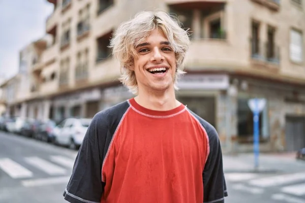 年轻的金发男子自信地站在街上笑 — 图库照片