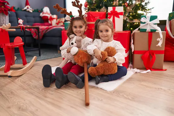 Duas Crianças Segurando Ursinho Sentado Chão Pela Árvore Natal Casa — Fotografia de Stock