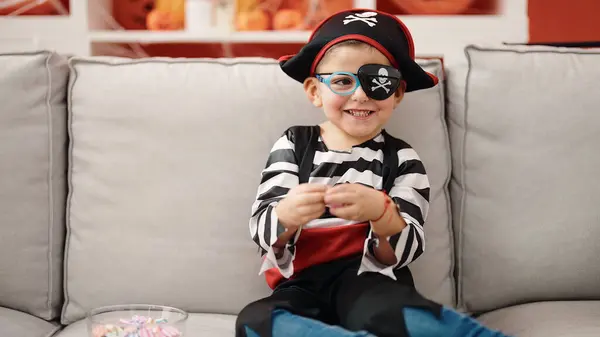 Adorable hispanic boy wearing pirate costume holding sweet at home