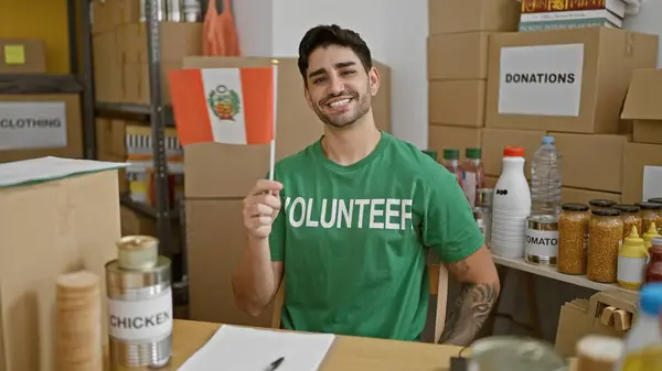 Joven Hombre Hispano Voluntario Sonriendo Confiado Sosteniendo Bandera Perú Centro — Foto de Stock