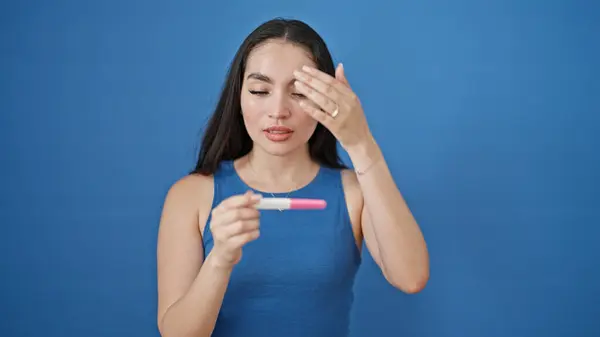 Młoda Piękna Latynoska Trzyma Test Ciążowy Patrząc Zdenerwowany Odizolowane Niebieskie — Zdjęcie stockowe