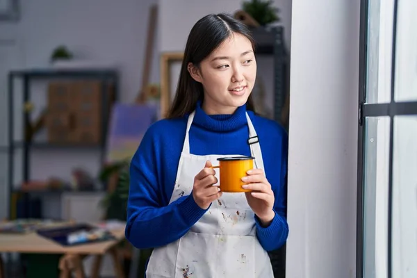 Chinese woman artist smiling confident drinking coffee at art studio