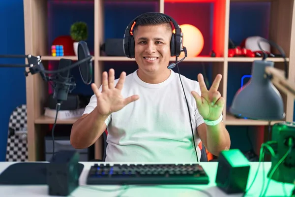 Молодой Латиноамериканец Играет Видеоигры Показывая Показывая Пальцами Номер Восемь Улыбаясь — стоковое фото