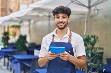 Young arab man waiter using touchpad working at restaurant