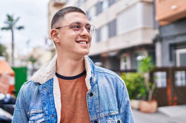 Young hispanic man smiling confident looking to the side at street