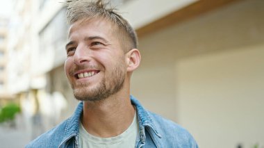 Young caucasian man smiling confident looking to the side at street