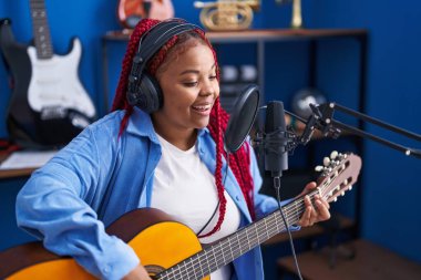 Afrikalı Amerikalı kadın müzisyen müzik stüdyosunda klasik gitar çalıyor.