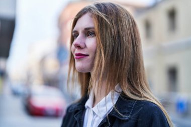 Sokakta ciddi bir ifadeyle yan tarafa bakan genç sarışın kadın.