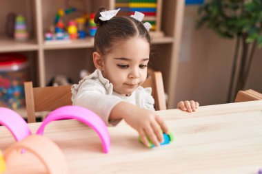 Anaokulundaki masada oturan, inşaat bloklarıyla oynayan sevimli İspanyol kız.