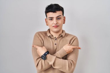 İzole edilmiş arkaplan üzerinde duran ikili olmayan kişi her iki tarafı da parmaklarıyla işaret ediyor. Farklı yönler farklı. 