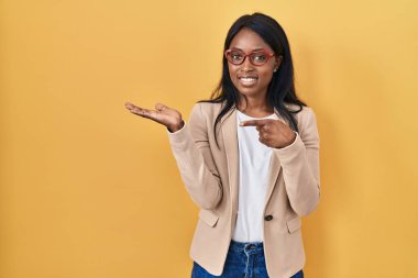 Gözlüklü Afrikalı genç bir kadın kameraya hayret ediyor ve gülümsüyor.. 