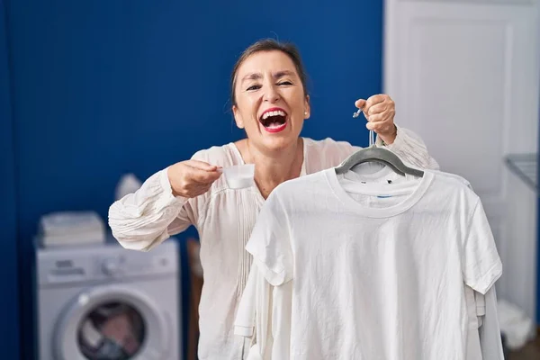 Middle Age Hispanic Woman Holding Shirt Hanger Detergent Powder Smiling — Stock Photo, Image