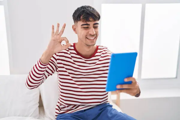 Joven Hombre Hispano Usando Touchpad Sentado Cama Haciendo Signo Con — Foto de Stock