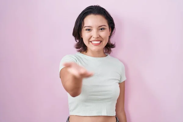 Spaanse Jonge Vrouw Staan Roze Achtergrond Glimlachend Vrolijk Aanbieden Palm — Stockfoto