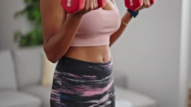 African american woman using dumbbells training at home