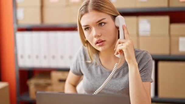 若い金髪女性Eコマースビジネスワーカーは オフィスで動揺しているラップトップを使用して電話で話す — ストック動画