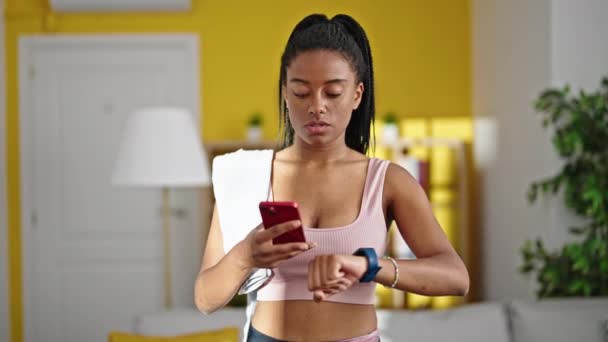 Africano Americano Mulher Vestindo Sportswear Usando Smartphone Olhando Relógio Casa — Vídeo de Stock
