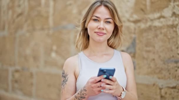 Jovem Mulher Loira Usando Smartphone Sorrindo Sobre Fundo Pedra Isolado — Vídeo de Stock