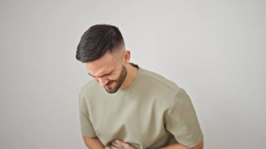 Karnı ağrıyan genç İspanyol bir adam izole edilmiş beyaz arka planda duruyor.