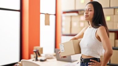 Young beautiful hispanic woman ecommerce business worker holding package at office
