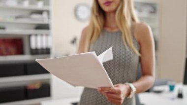 Genç sarışın iş kadını ofiste belge okuyor.
