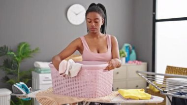 Çamaşır odasında elinde sepet tutan Afrikalı Amerikalı kadın.