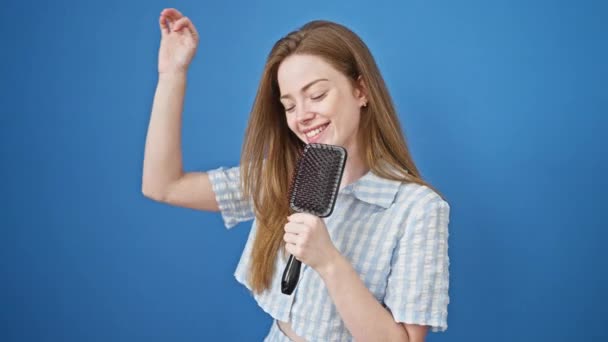Young Blonde Woman Singing Song Using Brush Microphone Isolated Blue — Stock Video