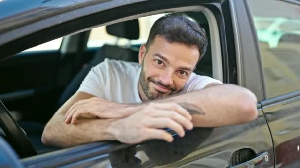 若いヒスパニック系の男が自信を持って路上で車の上に座って笑って — ストック動画