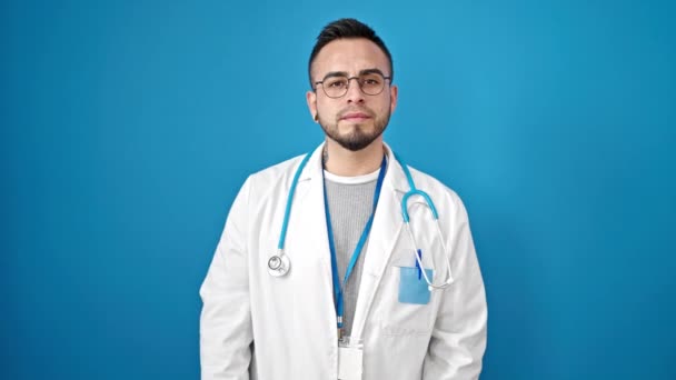孤立した青い背景の上に沈黙を求めるヒスパニック男性の医師 — ストック動画