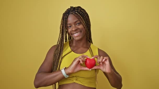 African American Woman Smiling Confident Holding Heart Chest Isolated Yellow — Stock Video