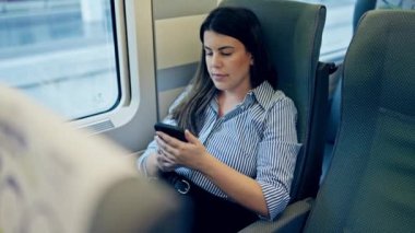 Trenin içinde akıllı telefon kullanan genç ve güzel bir İspanyol kadın.