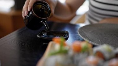 Genç, güzel İspanyol kadın restorana soja sosu döküyor.