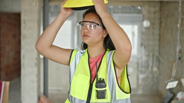 年轻的中国女建筑师戴着硬礼帽 面带微笑地环视四周的建筑工地 — 图库视频影像