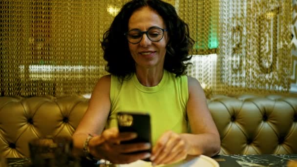 在餐馆用智能手机的中年惊慌失措女人 — 图库视频影像