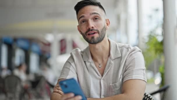 Hombre Hispano Joven Usando Teléfono Inteligente Sentado Mesa Hablando Terraza — Vídeo de stock