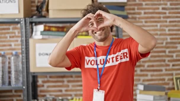 在慈善中心 身穿义工制服的青年惊慌失措者积极分子做着爱心手势 — 图库视频影像