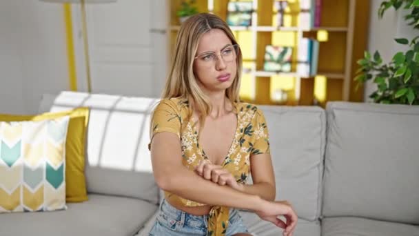 Young Blonde Woman Sitting Sofa Scratching Arm Itching Home — Stock Video