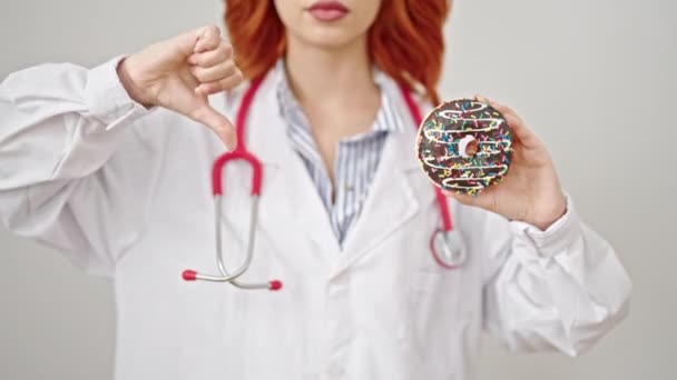Joven Pelirroja Doctora Sosteniendo Donut Haciendo Gesto Pulgar Hacia Abajo — Vídeos de Stock