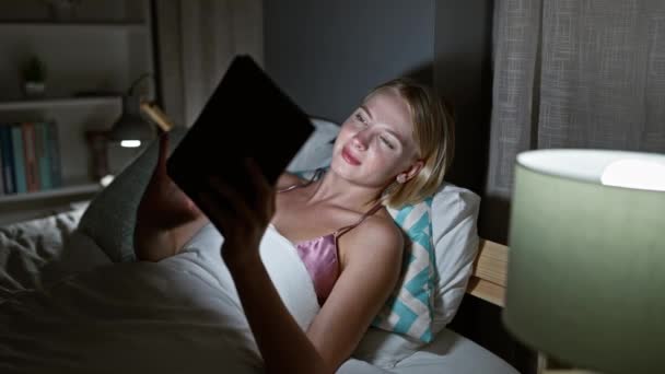 Młoda Blondynka Pomocą Touchpad Leżącego Łóżku Sypialni — Wideo stockowe