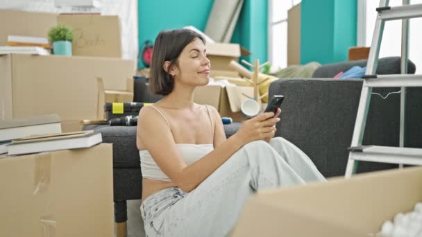 Young Beautiful Hispanic Woman Using Smartphone Sitting Floor New Home — Stock Video